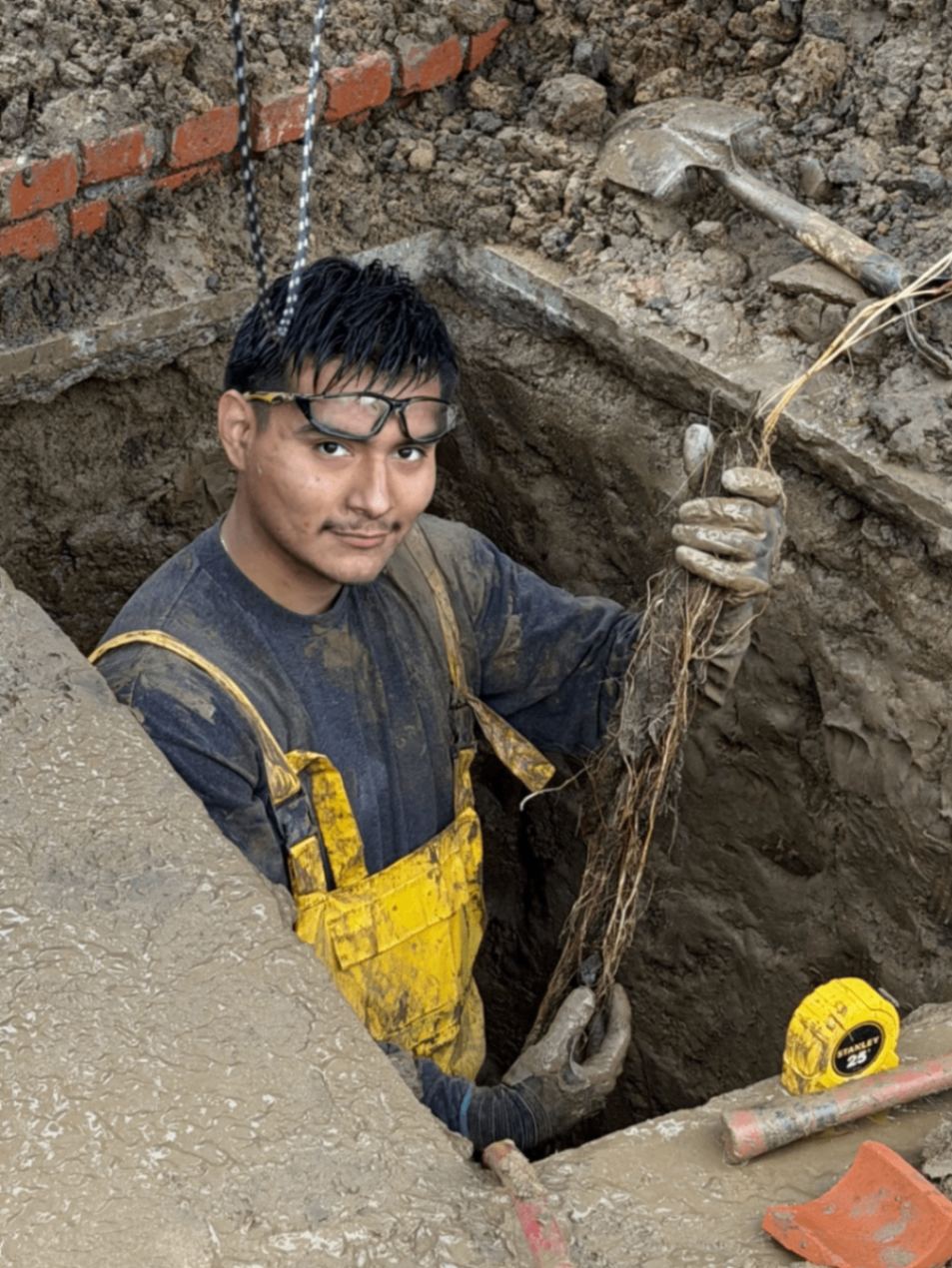 SpeeDee Drains technician in a deep excavation clearing tree roots from a broken sewer line in Orange County, CA