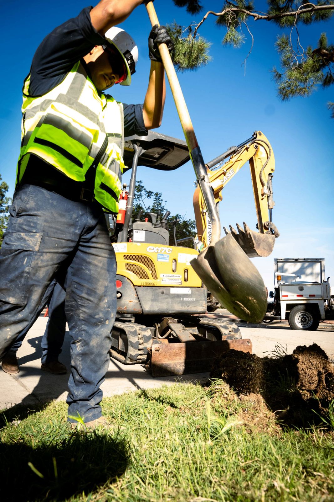 SpeeDee Drains field crew shoveling alongside a mini excavator during sewer excavation in Fullerton, CA